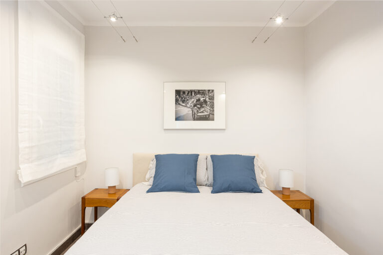 A bed room with two nightstands and a picture on the wall