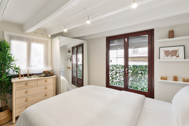 A bedroom with white walls and wooden furniture.