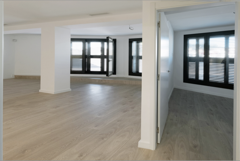A large empty room with white walls and wooden floors.