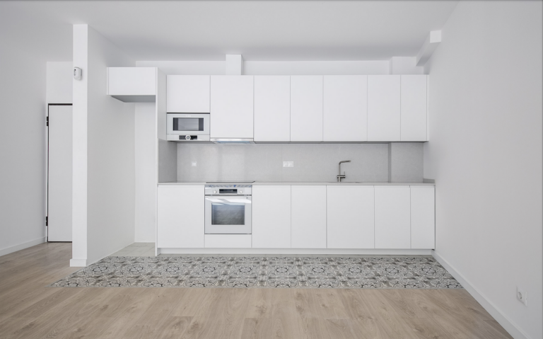 A kitchen with white cabinets and a wooden floor