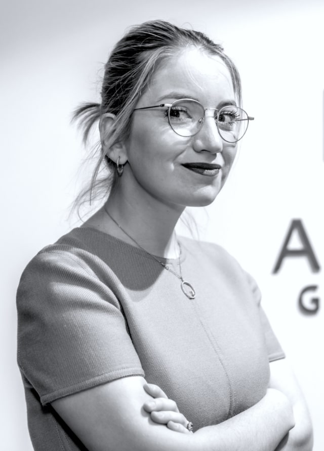 Black and white photo of smiling woman with glasses.