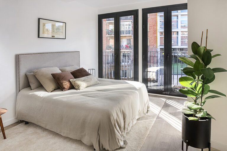 Bright bedroom with large windows and plants.