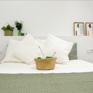 Cozy bed with pillows and decorative basket.